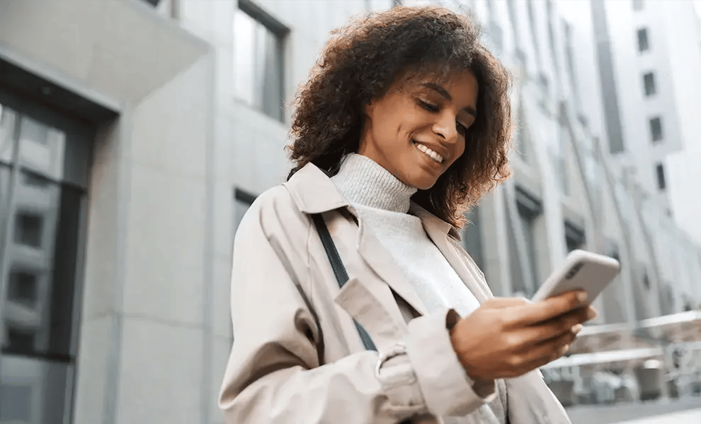 Person som står i stadsmiljö och använder mobiltelefon för att ta del av reseinformation.